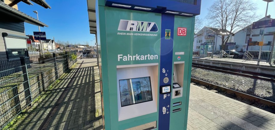 Fahrkartenautomat und im Hintergrund ein Bahnhof